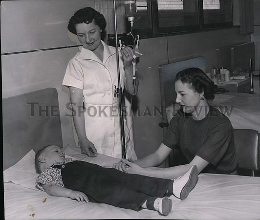 1957 Press Photo Mrs James Mohondo looks on son Pat a hemophiliac